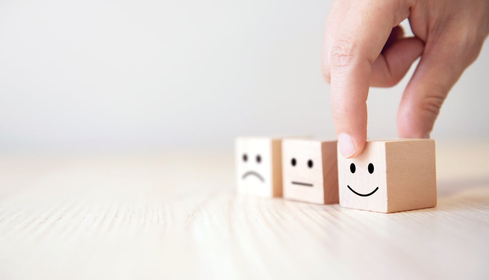 Close,Up,Customer,Hand,Choose,Smiley,Face,And,Blurred,Sad